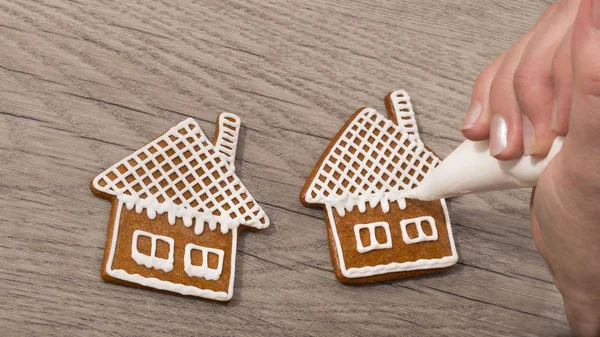 Gros plan d'une main féminine lors de la décoration de pains d'épices sucrés sur une table en bois — Photo