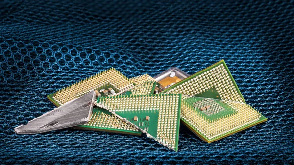 Gebroken computerprocessors op blauwe zeshoekige geweven gaas — Stockfoto