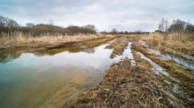 Çamurlu engebeli yol ve mavi gökyüzü ile ıssız askeri alanda bahar tezcan