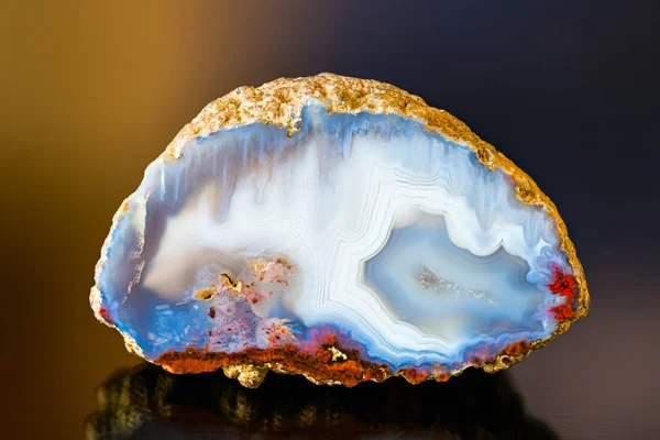 White blue agate gem cross section with reflection on dark colored background — Stock Photo, Image