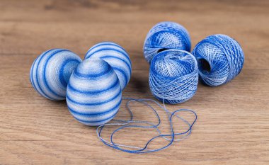 Blue colored striped Easter eggs and cotton yarn in decorative skeins on wooden background