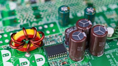 Toroidal çekirdek indüktörüne yakın çekim. Pasif elektrik bileşenleri. Elektronik indüksiyon bobini, bakır tel sarma, mikroçip, kapasitör ya da yeşil bilgisayar devre kartına lehimlenmiş rezistanslar..