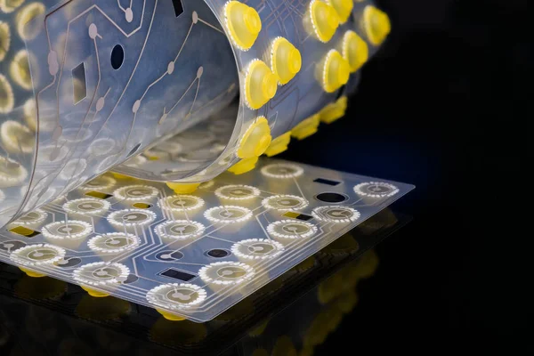 Klavye zarının içinde elektronik esnek devre kartı var. Silikon düğmeleri ayrıntıları. Esnek PCB plastik çarşafın kıvrımlı sanatsal hayatı. Siyah arkaplanda sarı kubbe anahtarlarının yansıması.