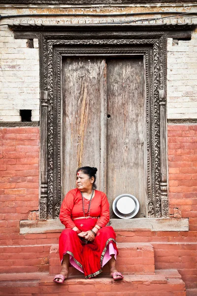 Mulher se senta na frente da porta de madeira, Kathmandu, Nepal — Fotografia de Stock