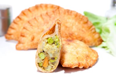 Haşlanmış bezelye, patates, havuç ve karnabahar ile doldurulmuş çıtır sebze Samosa tabakta servis edilir.