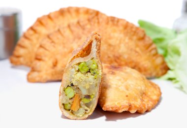 Haşlanmış bezelye, patates, havuç ve karnabahar ile doldurulmuş çıtır sebze Samosa tabakta servis edilir.