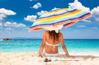 Güneş şapkalı güzel kadın plaj manzarasının keyfini çıkarıyor. Yunanistan.