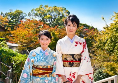 Kyoto - 24 Ekim 2014: Geleneksel kimonolu iki Japon kadın 24 Ekim 2014 'te Kyoto, Japonya' da sonbahar parkında. Sonbahar yapraklarına bakmak, Japonya 'da antik çağlardan kalma kültürel bir meşgaledir..