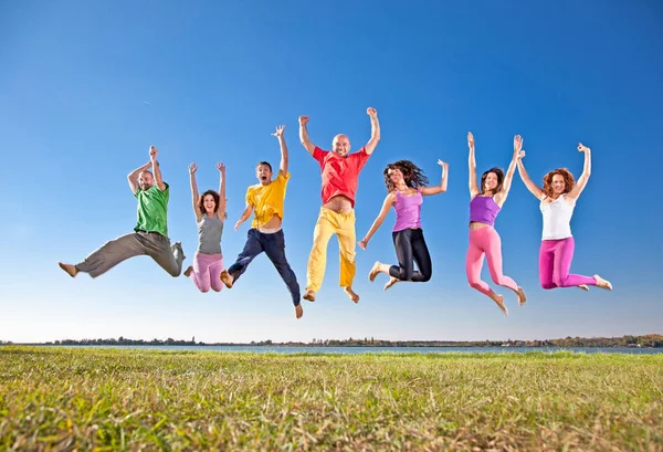 Feliz Grupo Sonriente Personas Saltando Orilla Del Lago — Foto de Stock