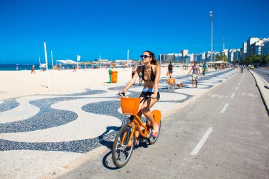 Rio De Janeiro, Brezilya - Nisan 24, 2015: Genç Brezilyalı kadın Copacabana Plajı'nda kaldırım boyunca bisikletsürmek. Rio de Janeiro , Brazia.