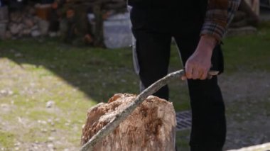 Küçük baltayla odun kesiyor.