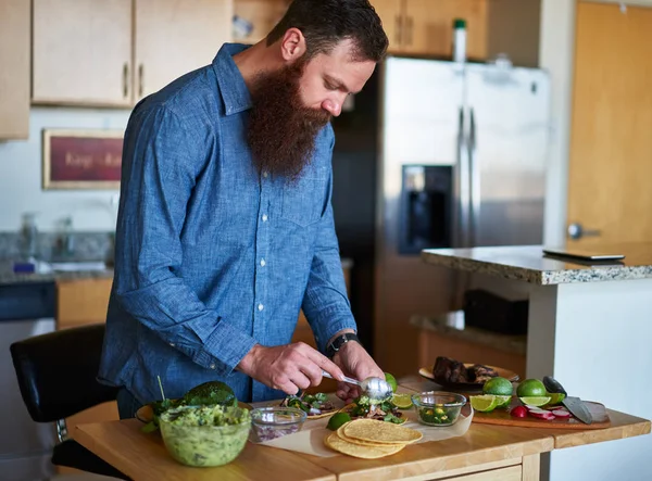 Uomo che aggiunge guacamole ai tacos fatti in casa — Foto Stock