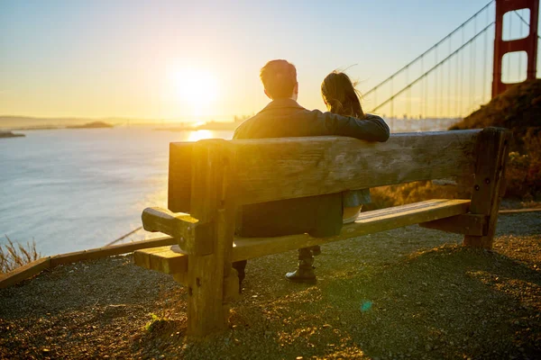 Casal sentado no banco assistindo nascer do sol — Fotografia de Stock