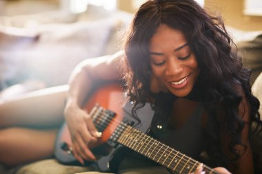 Kadın kanepede otururken gitar çalmak