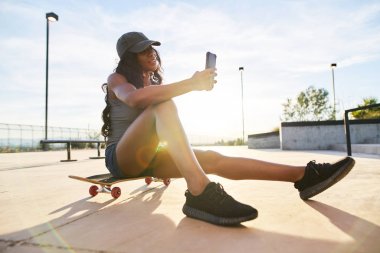 Selfie çekerken kaykay üzerinde oturan kadın 