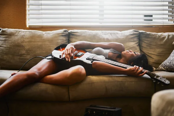 woman lying on couch with electric guitar on sofa