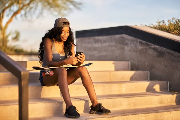 Happy african american woman sitting on steps at skatepark — Stock Photo, Image