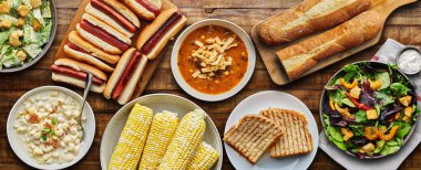 table top meal with hot dogs, grilled cheese, soup and salad in flat lay composition clipart