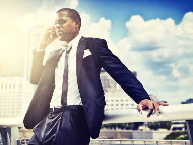 Takım elbiseli, akıllı telefonlu Afrikalı adam.;