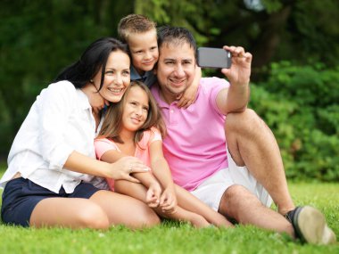 Aile parkta akıllı telefonla selfie çekiyor.