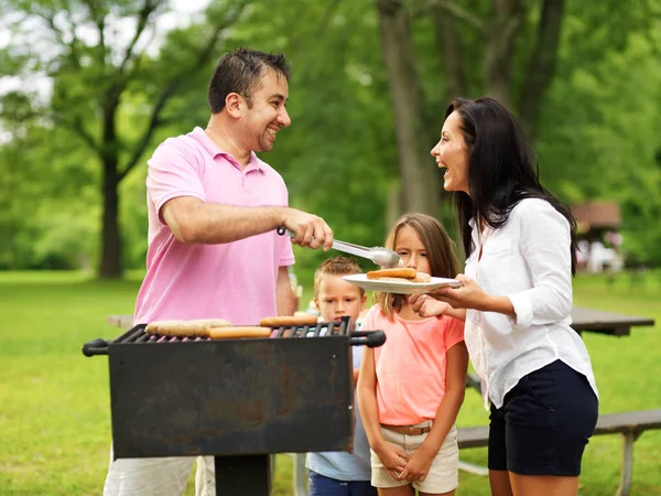 family cookout - dad giving mom food on platter from grill