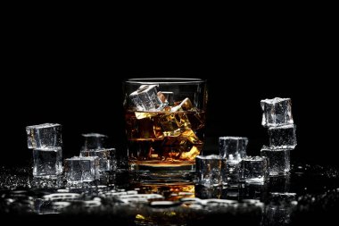 Yukarıdan siyah arkaplanlı buzlu viski. Siyah arkaplanda bir bardak viski ve buz.