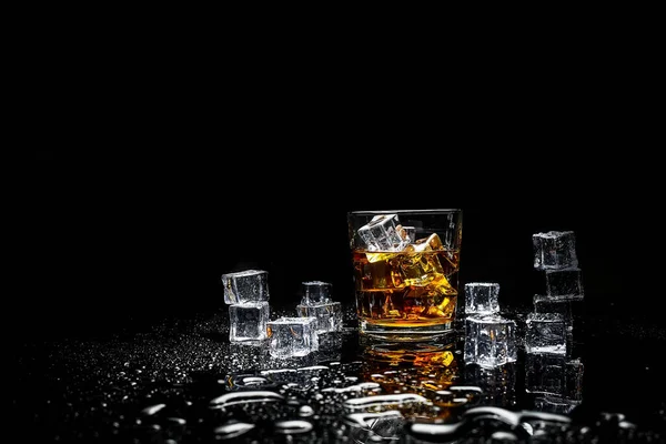 Whiskey with ice cubes on black background from above.Glass of scotch and ice cubes on a on black background