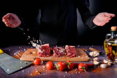 Erkeklerin elleri, çiğ ete baharat katıyor.