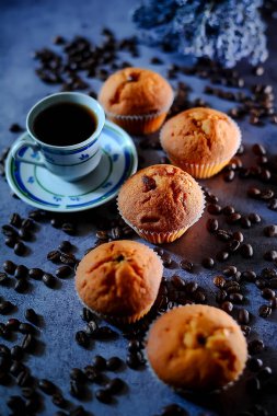 Kahve fincanı ve siyah arka planda çörekler..