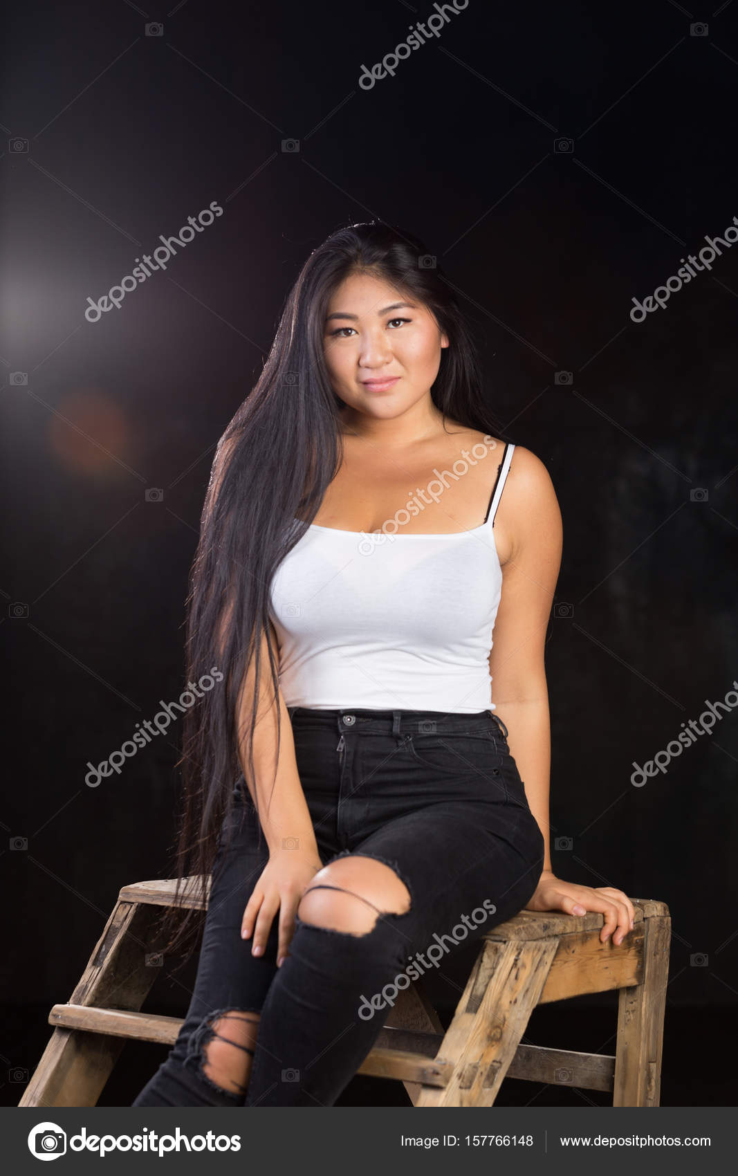 Beautiful curvy girl with dark hair and cheerful personality in a white  t-shirt on a dark background Stock Photo - Alamy