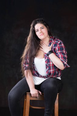 Rahat bir kıyafet içinde karanlık bir uzun saçlı güzel artı boyutu modeli