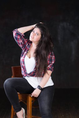Rahat bir kıyafet içinde karanlık bir uzun saçlı güzel artı boyutu modeli
