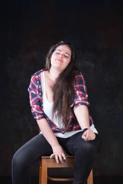 Rahat bir kıyafet içinde karanlık bir uzun saçlı güzel artı boyutu modeli