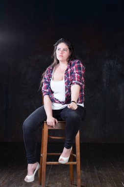 Rahat bir kıyafet içinde karanlık bir uzun saçlı güzel artı boyutu modeli