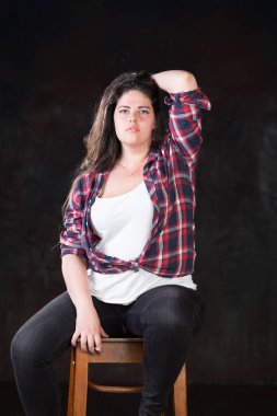 Rahat bir kıyafet içinde karanlık bir uzun saçlı güzel artı boyutu modeli