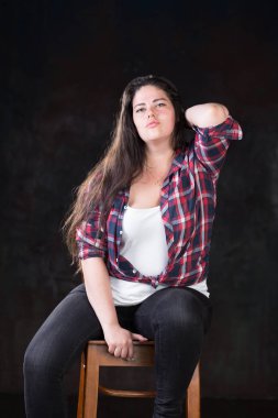 Rahat bir kıyafet içinde karanlık bir uzun saçlı güzel artı boyutu modeli