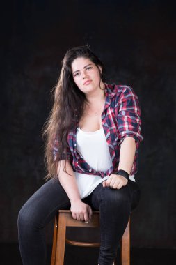 Rahat bir kıyafet içinde karanlık bir uzun saçlı güzel artı boyutu modeli