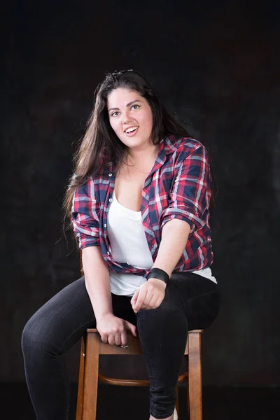 Beautiful plus size model with a dark long hair in a casual outfit