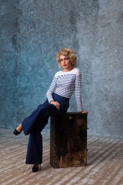 Eski bir sandık üzerinde oturan bir denizci olarak zarif çekici kadın modeli tarz