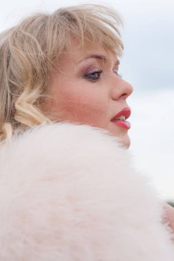 Genç sarışın kadın bej elbise ve kırsal yolda kısa pembe kürk manto