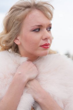 Genç sarışın kadın bej elbise ve kırsal yolda kısa pembe kürk manto