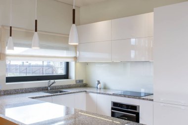 Ahşap aksan ile hafif iç modern mutfak mobilyaları tasarımı. Mutfakta ki yarımada odada. Taş yüzey. Parlak cepheler. Proje bitti. Beyaz kolye ışığı. Lavabo, pencere, panjur. Cam.