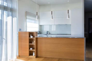 Ahşap aksan ile hafif iç modern mutfak mobilyaları tasarımı. Mutfakta ki yarımada odada. Taş yüzey. Parlak cepheler. Proje bitti. Beyaz kolye ışığı. Lavabo, pencere, panjur. Cam.