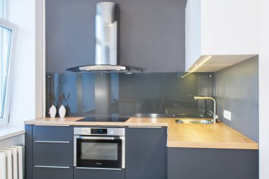 Modern ev iç. Hafif iç ahşap desenli modern mutfak tasarımı. LED ışıklar. Avrupa mobilya, tasarım, teknoloji. Boyalı cephe. Mutfak cam geri duvar.
