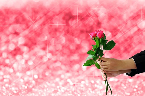 Hands holding red rose flower on red lights festive blurry and b — Stock Photo, Image