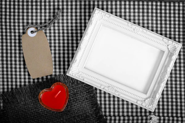 empty white frame next red heart sign from candle and paper tag