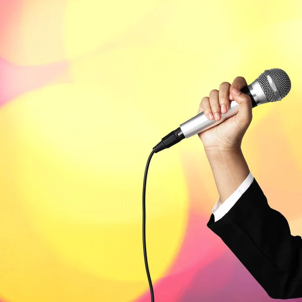 Woman hand holding microphone on blur bokeh background — Stock Photo, Image