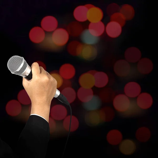 Hand holding microphone on blur bokeh background — Stock Photo, Image
