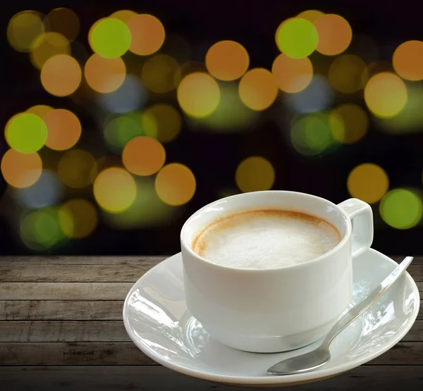 Горячий кофе в белой чашке на дереве с размытым светом — стоковое фото