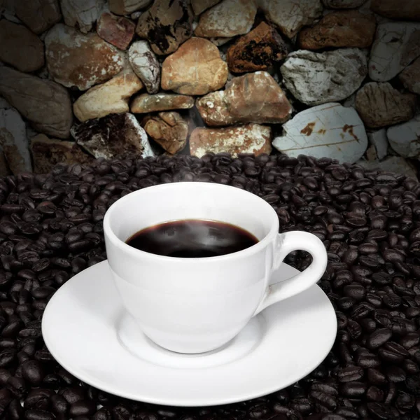 Café preto e grãos de café com fumaça na parede de pedra — Fotografia de Stock